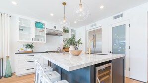 Una cucina moderna con mobili bianchi, un'isola in marmo ed elettrodomestici in acciaio inossidabile.