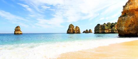 A beach with clear turquoise water, sandy shore, and rock formations.