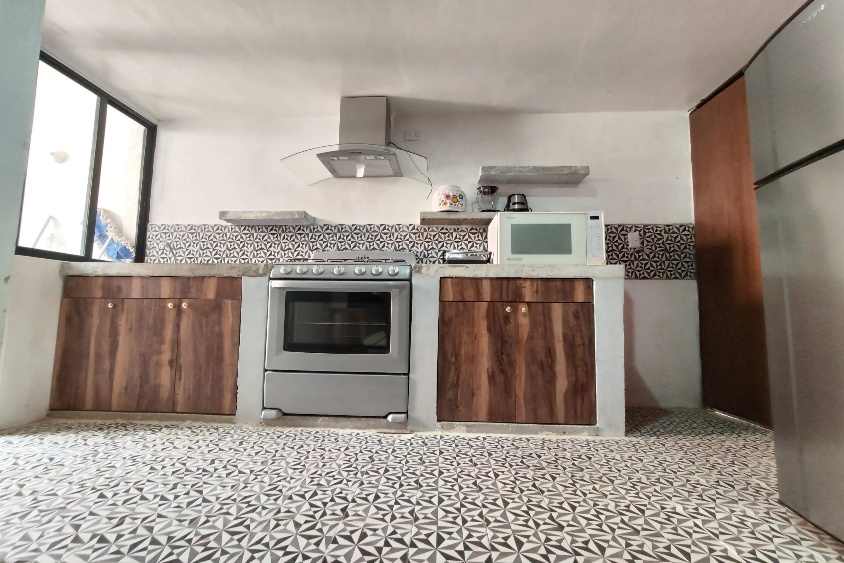 Una cocina con estufa, horno, microondas y armarios.