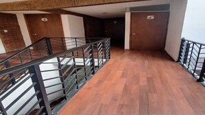 Una escalera con piso de madera y barandas de metal, que conduce a una puerta con el número 6.