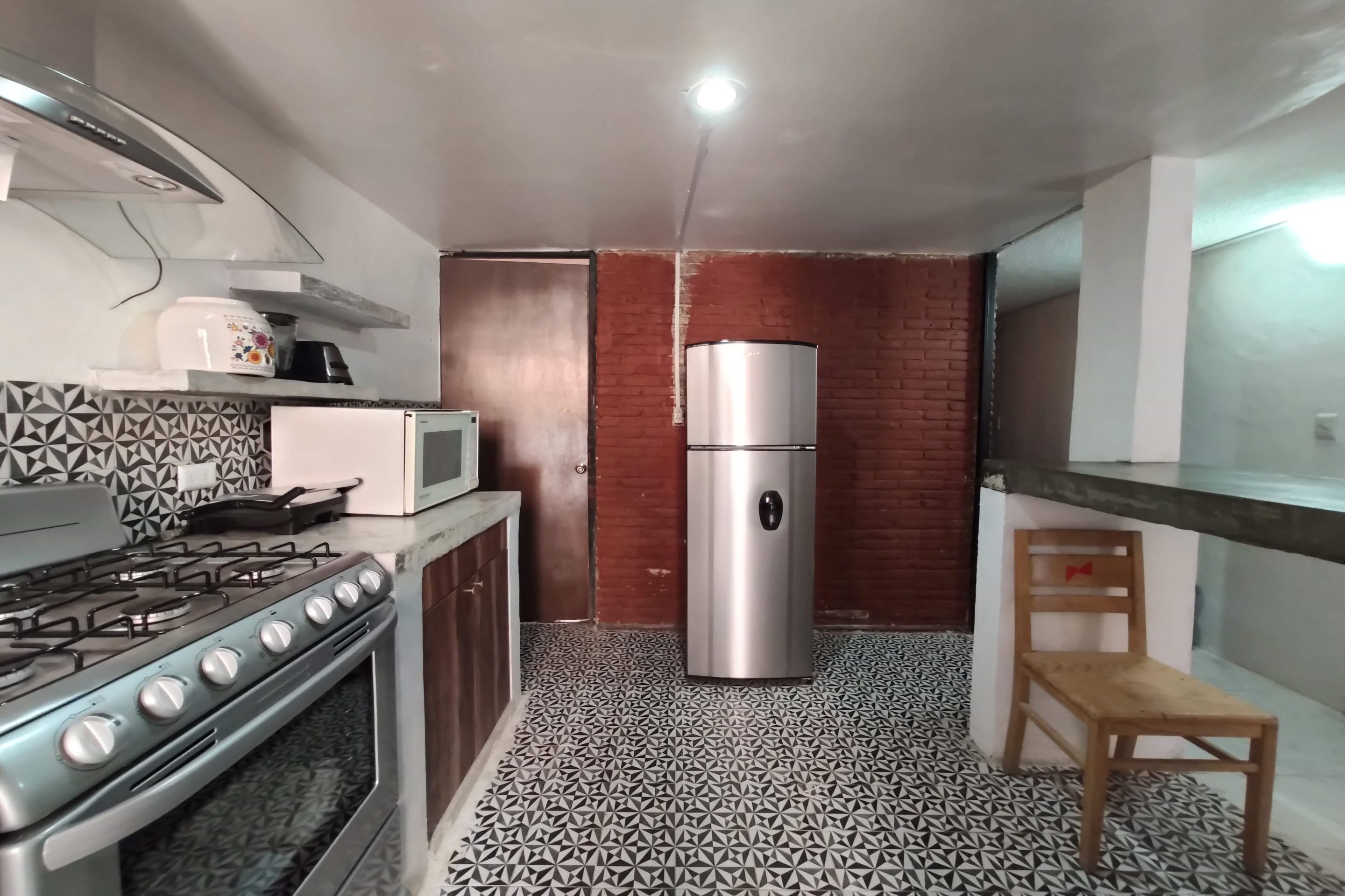 A compact kitchen with a gas stove, oven, microwave, and a refrigerator.