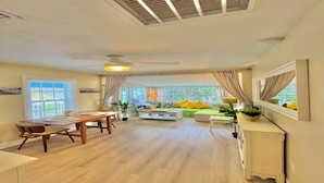 Amplia sala de estar con mesa de comedor, sofá y ventanas grandes.
