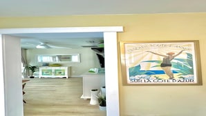Un pasillo que lleva a una sala de estar con un armario blanco, un espejo y un cartel en la pared.