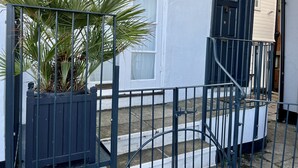 A white building with a black door and a sign that reads "Snugglers College." - Georgian Seafront fisherman’s cottage | Sea views | Old Town (Hastings)