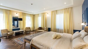 Habitación de hotel con una cama grande, dos sillones, una mesita y un televisor.