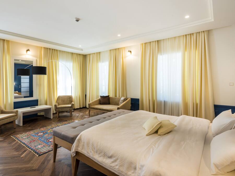 Habitación de hotel con una cama grande, dos sillones, una mesita y un televisor.