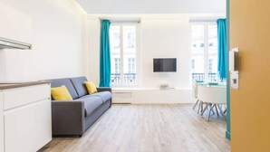 A modern living room with a sofa, a dining table, and a TV. - Apartment Paris Center "Marais" - 4 people (Paris)