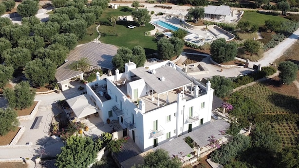 An aerial view of a property with a large white building, a swimming pool, and surrounding greenery. - Masseria Sottomasi (Fasano)