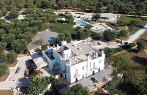 An aerial view of a property with a large white building, a swimming pool, and surrounding greenery. - Masseria Sottomasi (Fasano)