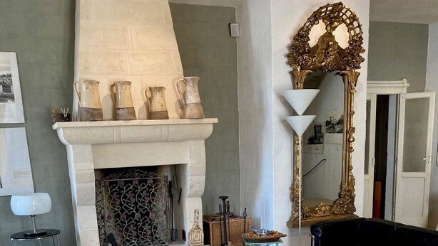 A living room with a fireplace, a black leather chair, a white sofa, and a patterned rug. - Masseria Sottomasi (Fasano)