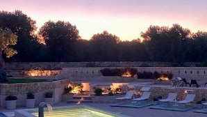 An outdoor swimming pool with lounge chairs and a stone wall in the background. - Masseria Sottomasi (Fasano)