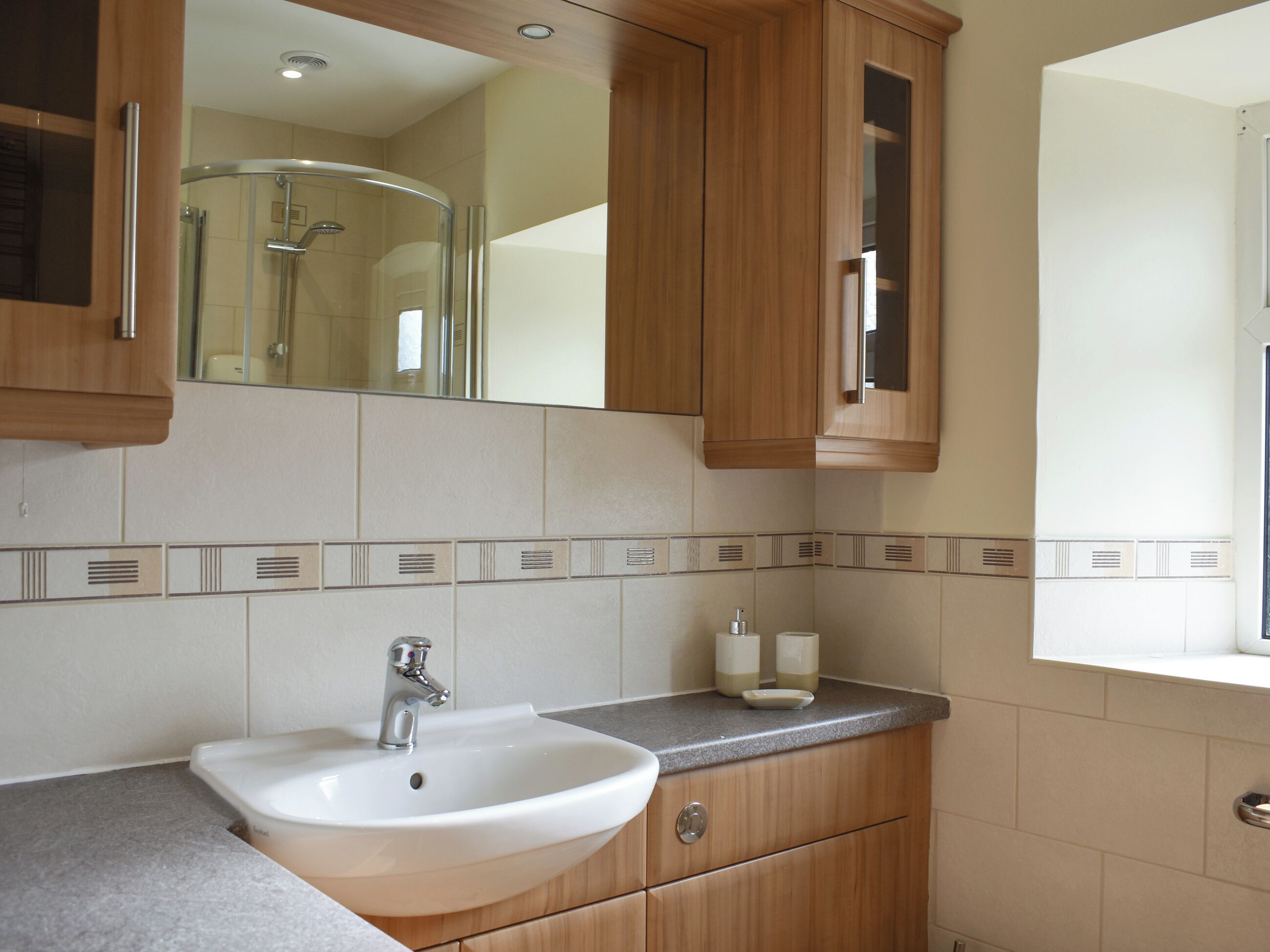 Une salle de bain avec un lavabo, un miroir et des meubles en bois.