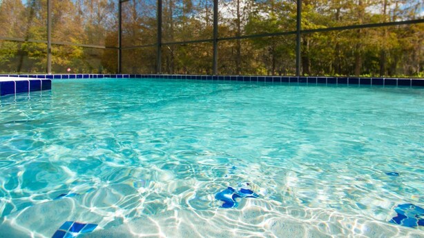 A clear swimming pool with blue tiles and a metal fence. - 3 Bed 258 (Kissimmee)