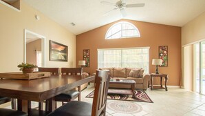 A spacious living room with a dining area, a ceiling fan, and a large window providing natural light. - 3 Bed 258 (Kissimmee)