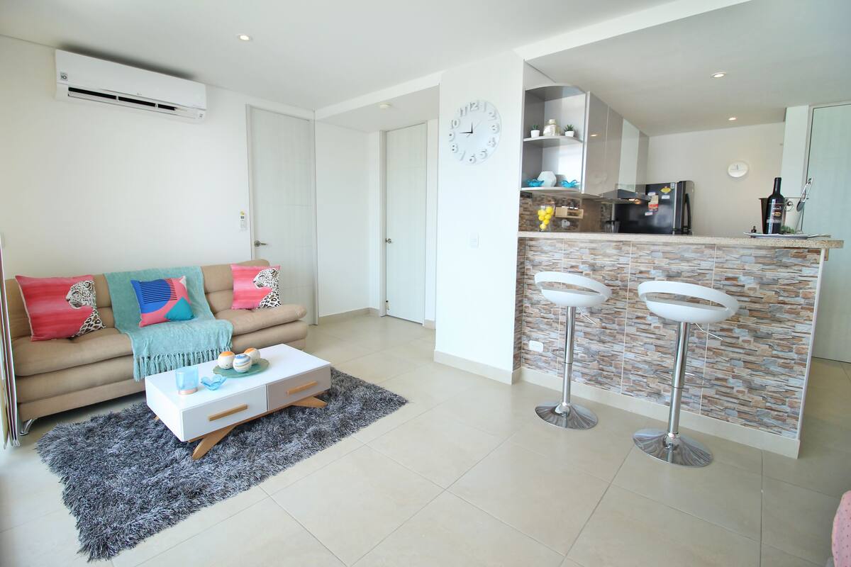 A modern living room with a sofa, coffee table, and two bar stools.
