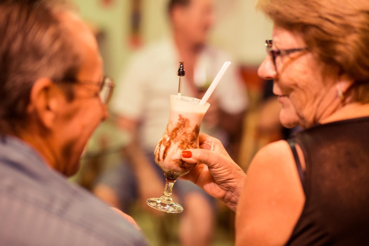 Una persona sosteniendo una copa de cóctel con una pajita.
