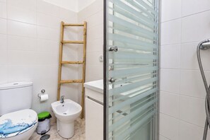 A bathroom with a toilet, bidet, and a glass shower enclosure.