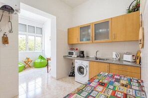 A compact kitchen with wooden cabinets, a washing machine, and a microwave. - Flat with one bedroom in Moscavide - Lisboa (Loures)