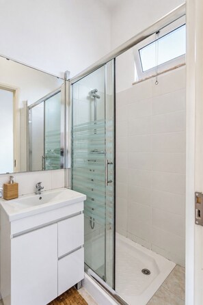 A modern bathroom with a glass-enclosed shower, a white sink, and a mirror.