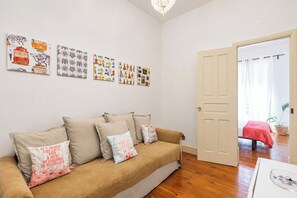 A cozy living room with a beige sofa, a wooden floor, and a door leading to another room. - Flat with one bedroom in Moscavide - Lisboa (Loures)