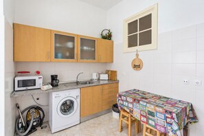A compact kitchen with a microwave, coffee maker, sink, and a table covered with colorful magazines. - Flat with one bedroom in Moscavide - Lisboa (Loures)