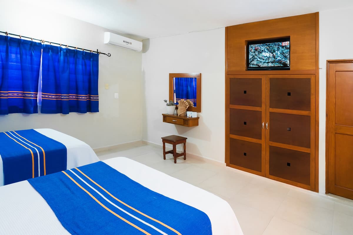A hotel room with two beds, a TV, a wardrobe, and a small table.