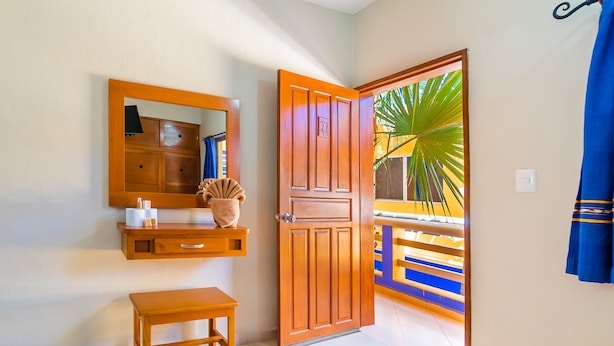 Een kamer met een houten deur, een spiegel, een klein houten tafeltje en een bank.