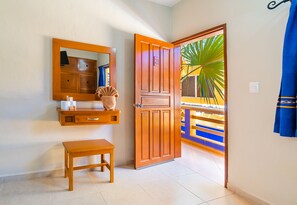 Une pièce avec une porte en bois, un miroir, une petite table en bois et un banc.