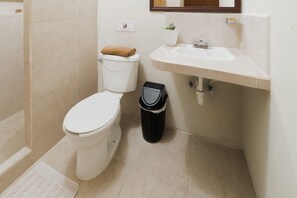 A bathroom with a toilet, sink, and trash bin.