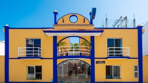 Een geel gebouw met een blauwe gevel, een centrale boog en balkons.