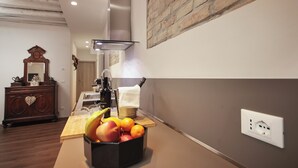 A kitchen with a fruit bowl, a stove, and a brick wall. - SARA'S LUXURY HOME 5 minutes from St Mark's Square (Venice)