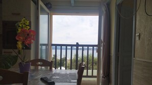 A dining area with a table, chairs, and a potted plant. A remote control is on the table. - F2 apartments with panoramic sea views (corse)