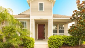 A two-story house with a front porch, a red door, and a mailbox.