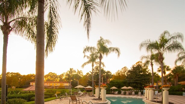 A pool area with tiled flooring, lounge chairs, and palm trees. - Private Screened Splash Pool Overlooking Tranquil Lake Right Beside Disney World by Florida Dream Homes (Kissimmee)