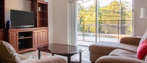 Una sala de estar con televisor, mueble de madera para entretenimiento y dos sofás.