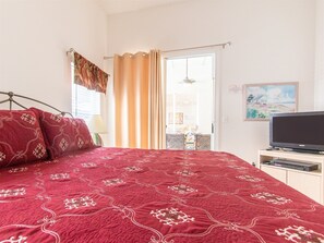 A bedroom with a large bed, a television, and a painting on the wall.