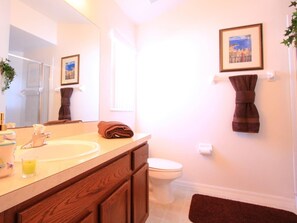 A bathroom with a wooden vanity, a mirror, a sink, a toilet, and a framed picture on the wall. - 4 Bed 4419 (Kissimmee)