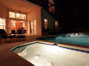 A swimming pool with a hot tub, surrounded by outdoor seating and a covered patio area.