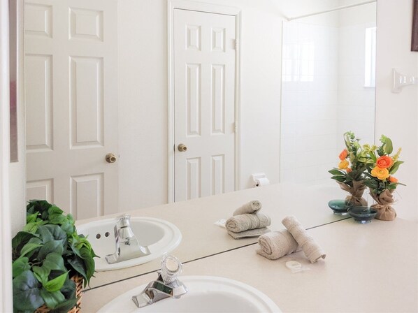 A bathroom with two sinks, a mirror, and a potted plant.