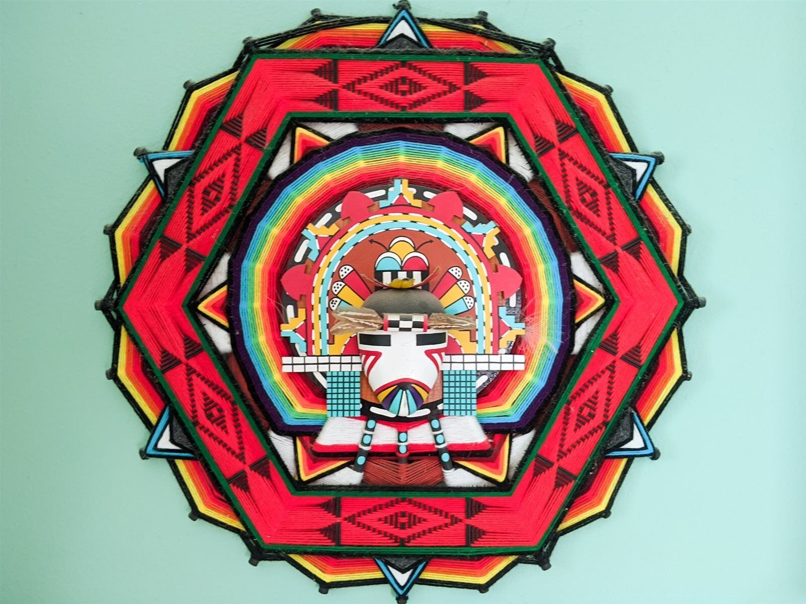 Vrolijke geometrische wanddecoratie met een centrale figuur.