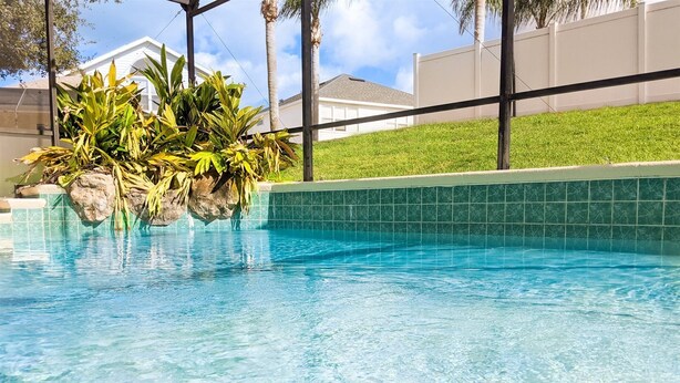 A clear blue pool with a rock feature and tropical plants. - 4 Bed 2269 (Kissimmee)