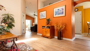 A spacious living room with wooden flooring, a dining table, and a sofa. There are two framed pictures on the wall, a potted plant, and a vase with dried flowers. - 3 Bed 156 (Davenport)