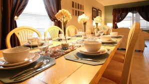 A dining room with a long wooden table set for a meal, yellow chairs, and a chandelier. - 5 Bed 722 (Davenport)