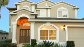 A two-story house with a beige facade, a brown front door, and a garage. - 5 Bed 722 (Davenport)