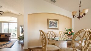 A dining area with a glass table, four chairs, a chandelier, and a framed picture on the wall. - 4 Bed 428 (Davenport)