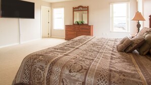 A bedroom with a large bed, a dresser, a TV mounted on the wall, and a ceiling fan. - 5 Bed 388 (Davenport)