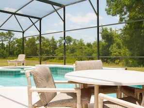 A covered outdoor area with a pool, seating, and a view of trees. - 5 Bed 388 (Davenport)