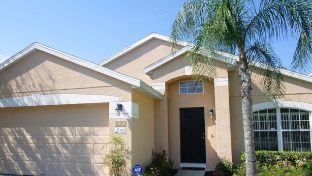 A single-story house with a beige exterior, a black front door, and a garage. - 4 Bed 231 (Davenport)