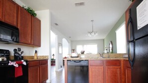 A modern kitchen with wooden cabinets, a black refrigerator, and a dishwasher. - 5 Bed 4720 (Kissimmee)