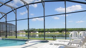 A pool area with a clear view of a lake and houses in the background. - 5 Bed 4720 (Kissimmee)